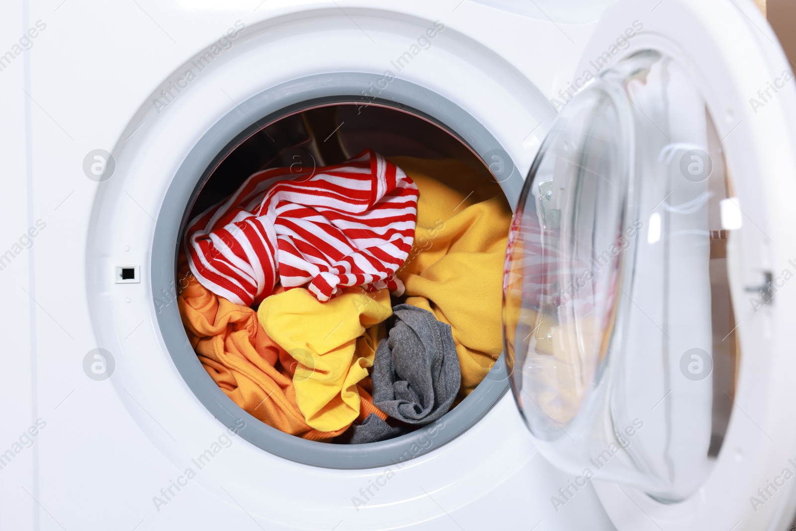 Photo of Modern washing machine with clothes in drum, closeup