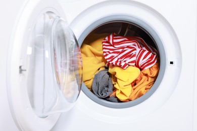 Photo of Modern washing machine with clothes in drum, closeup