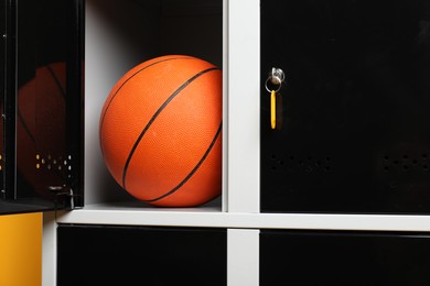 Photo of Open locker with basketball ball on orange background, closeup