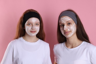 Photo of Teenage girls with masks on their faces and headbands against pink background