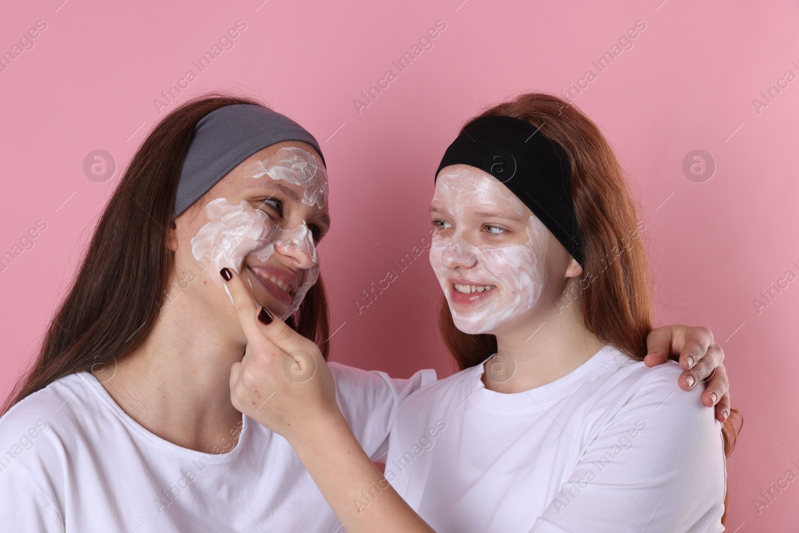 Photo of Teenage girls with masks on their faces and headbands against pink background