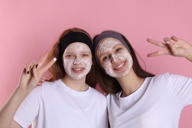 Photo of Teenage girls with masks on their faces and headbands against pink background