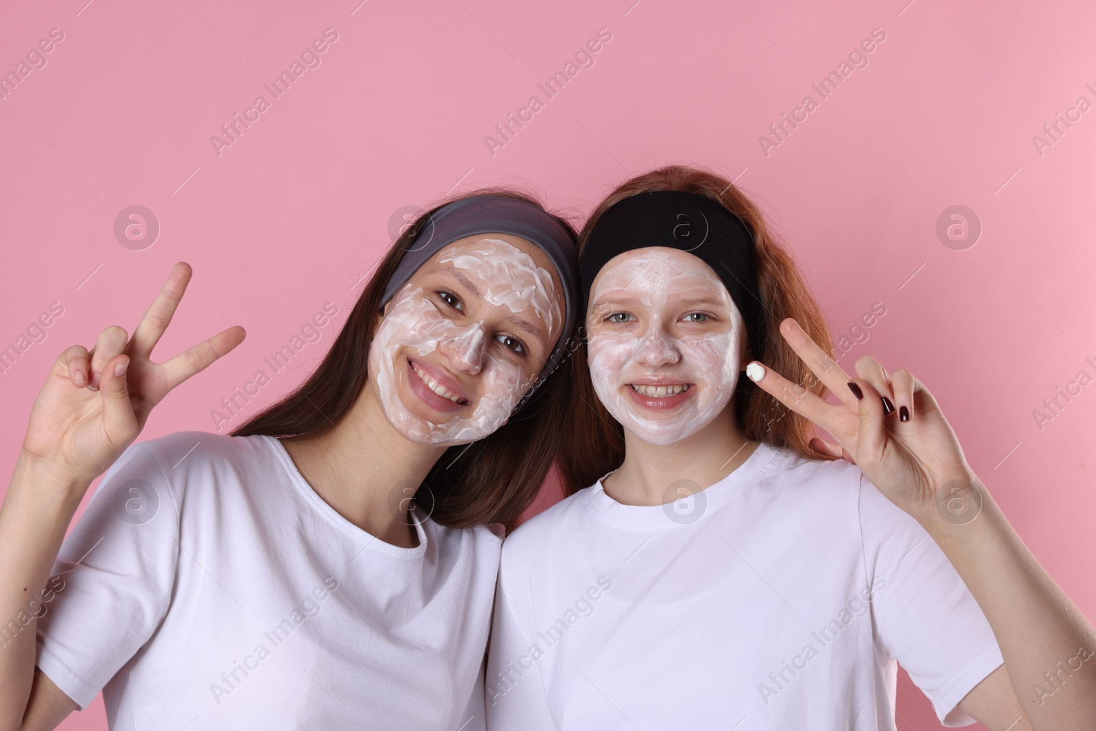 Photo of Teenage girls with masks on their faces and headbands against pink background