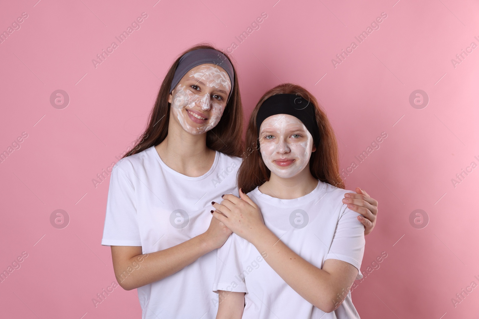 Photo of Teenage girls with masks on their faces and headbands against pink background