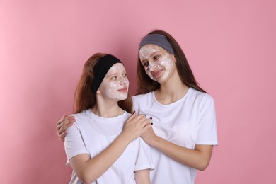 Teenage girls with masks on their faces and headbands against pink background