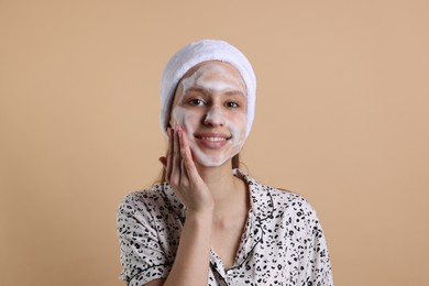 Photo of Teenage girl washing her face with cleanser on beige background. Cosmetic product