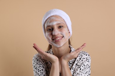 Teenage girl washing her face with cleanser on beige background. Cosmetic product