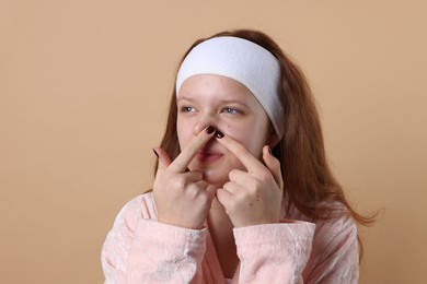 Photo of Teenage girl popping pimple on her face against beige background. Acne problem