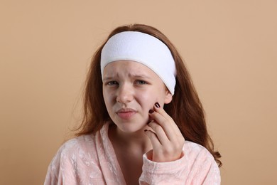 Photo of Teenage girl suffering from acne against beige background