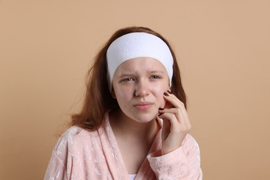 Photo of Teenage girl suffering from acne against beige background