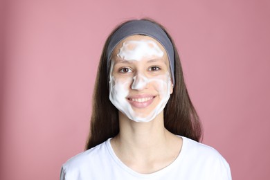 Photo of Teenage girl with cleansing foam on her face against pink background. Acne treatment