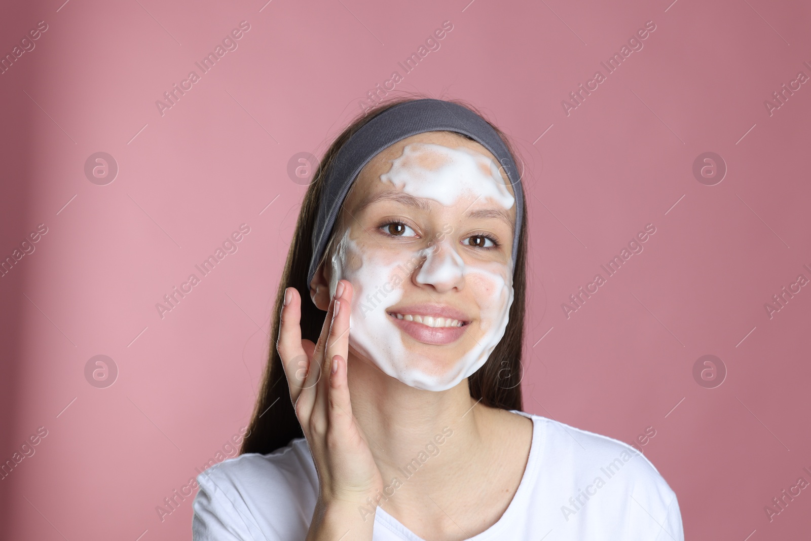 Photo of Teenage girl with cleansing foam on her face against pink background. Acne treatment