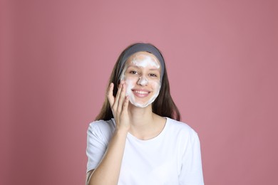 Photo of Teenage girl with cleansing foam on her face against pink background. Acne treatment