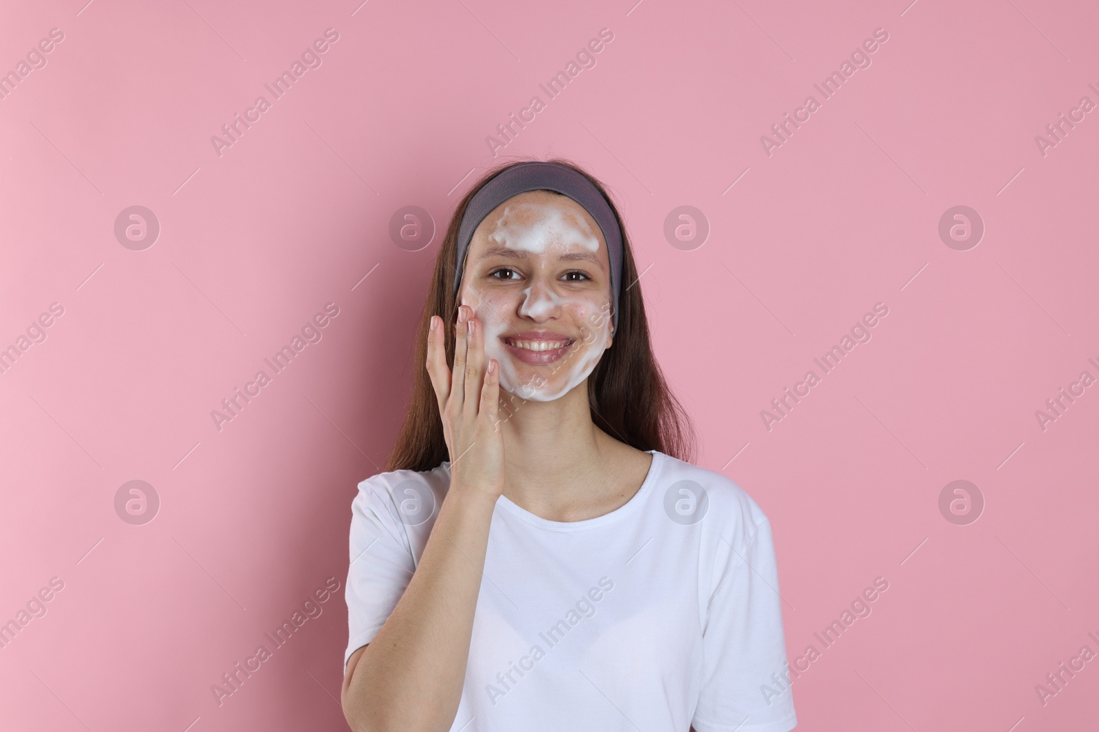 Photo of Teenage girl with cleansing foam on her face against pink background. Acne treatment