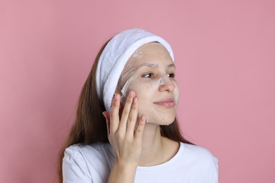 Photo of Teenage girl with sheet facial mask on pink background. Acne treatment