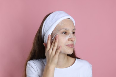 Photo of Teenage girl with sheet facial mask on pink background. Acne treatment