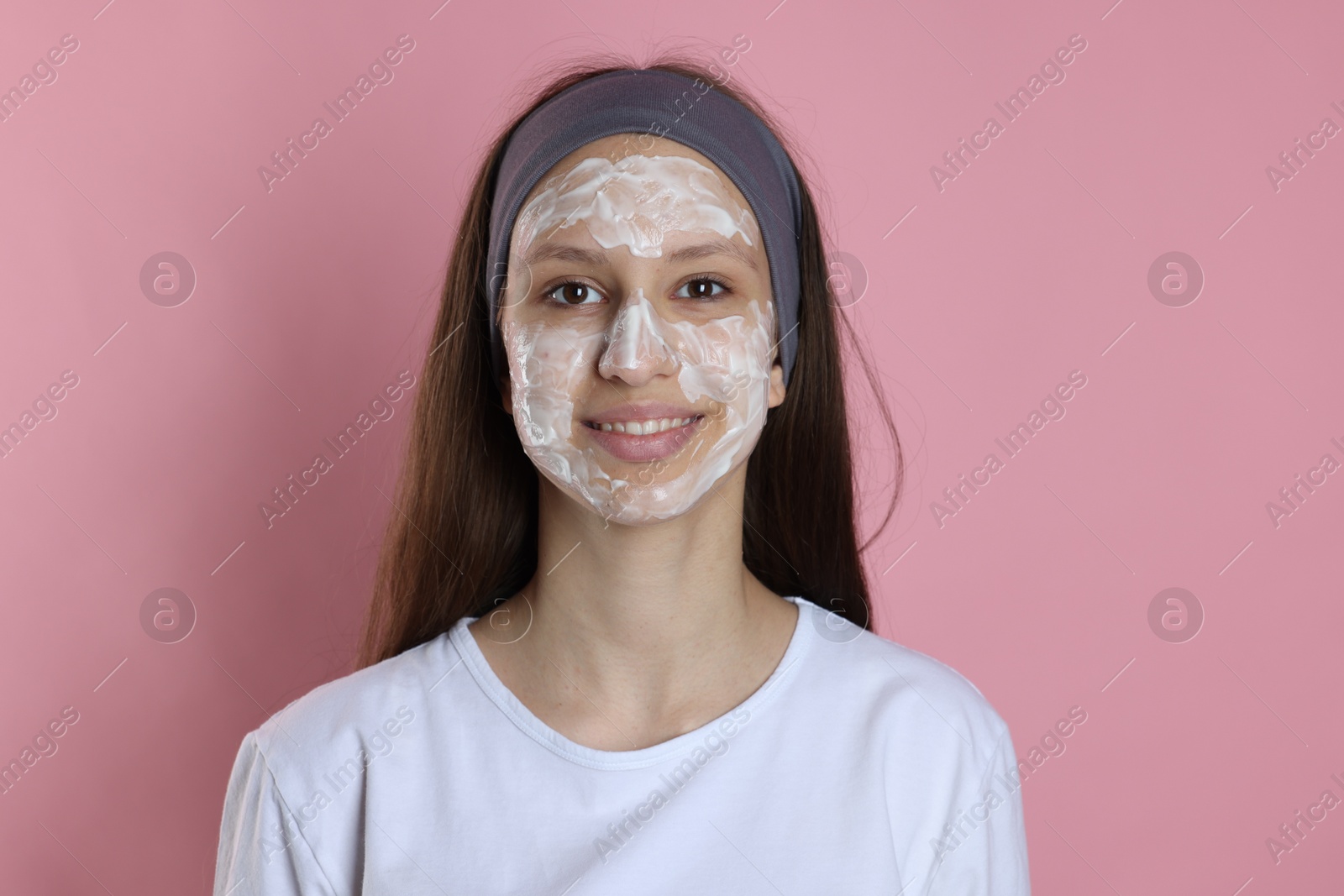 Photo of Teenage girl with cream on her face against pink background. Acne treatment