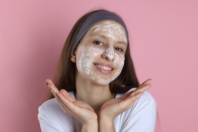 Photo of Teenage girl with cream on her face against pink background. Acne treatment