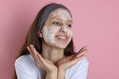 Photo of Teenage girl with cream on her face against pink background. Acne treatment