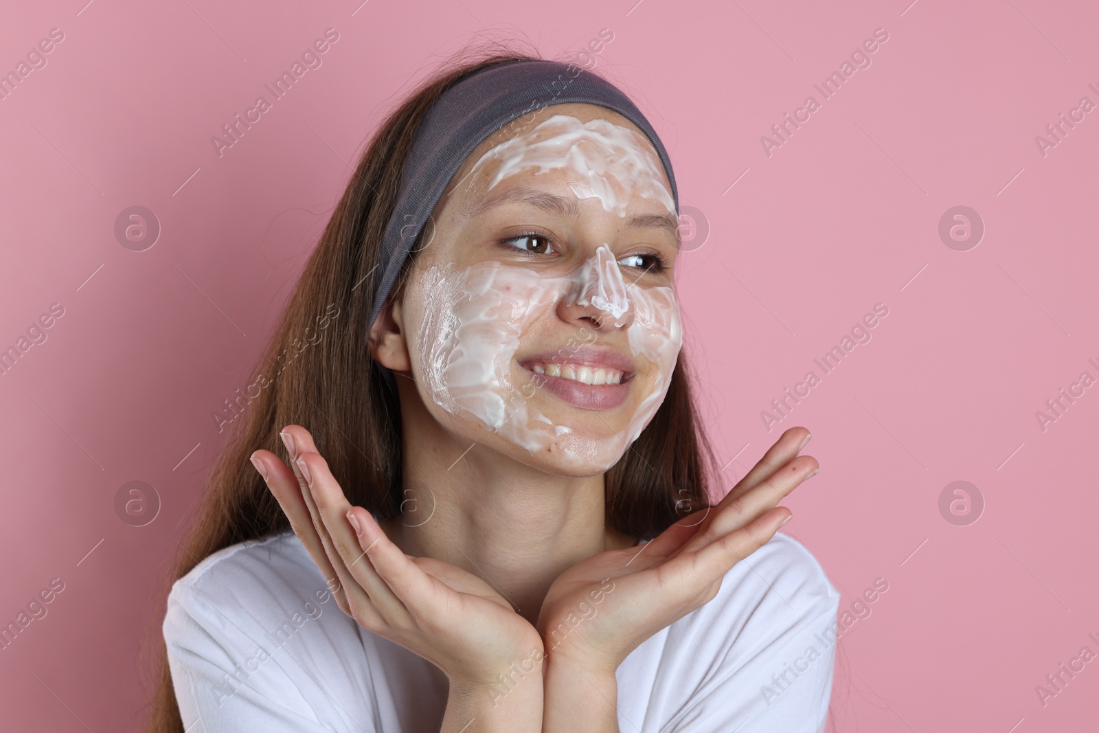 Photo of Teenage girl with cream on her face against pink background. Acne treatment