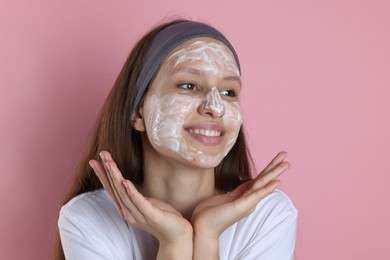 Photo of Teenage girl with cream on her face against pink background. Acne treatment