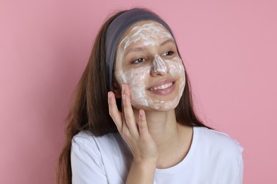 Photo of Teenage girl with cream on her face against pink background. Acne treatment