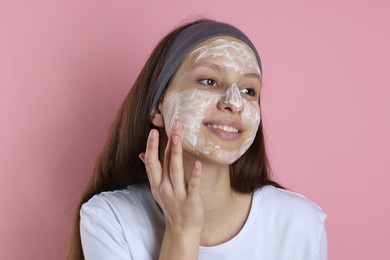 Photo of Teenage girl with cream on her face against pink background. Acne treatment