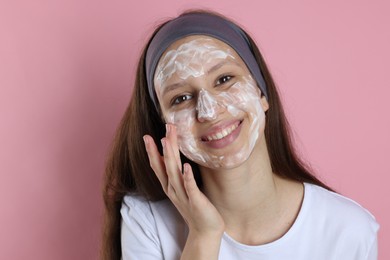 Photo of Teenage girl with cream on her face against pink background. Acne treatment