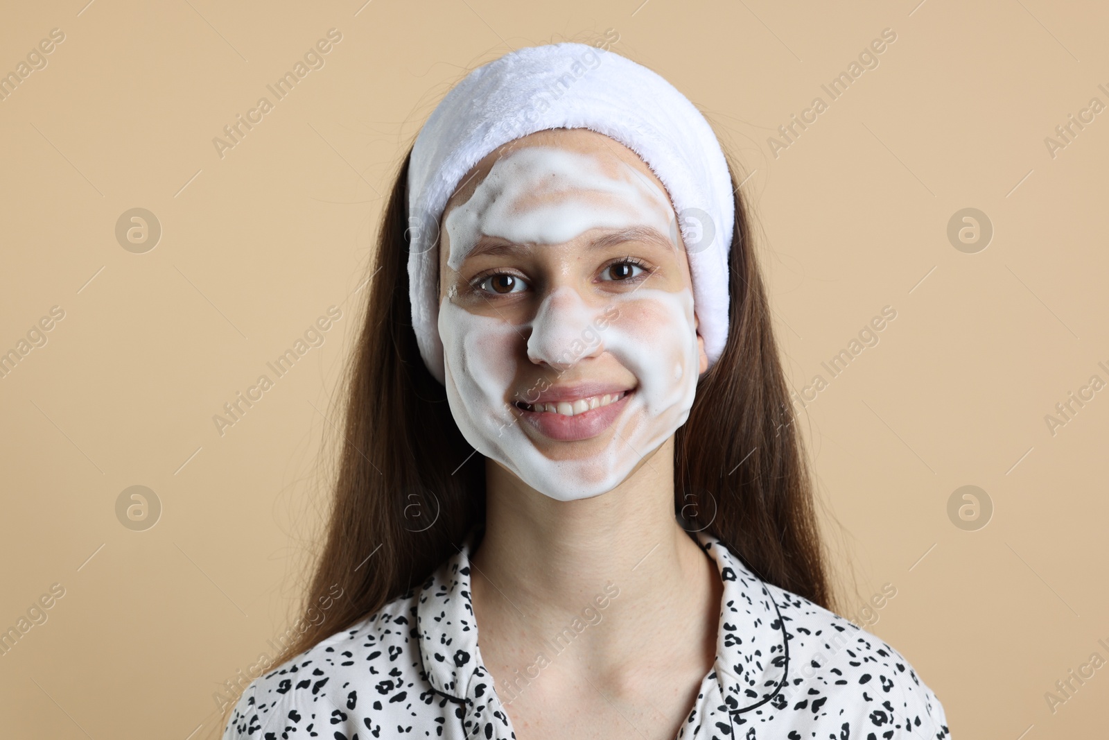 Photo of Teenage girl with cleansing foam on her face against beige background. Acne treatment