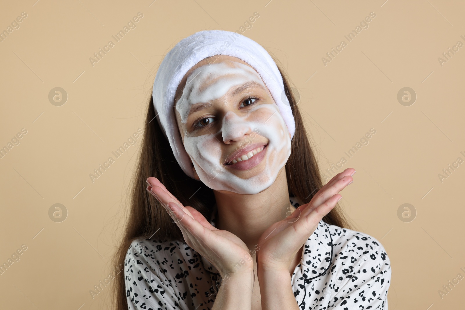 Photo of Teenage girl with cleansing foam on her face against beige background. Acne treatment