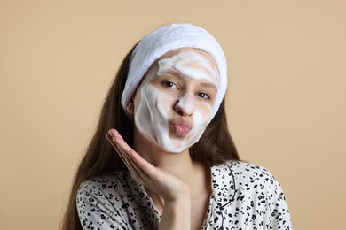 Photo of Teenage girl with cleansing foam on her face against beige background. Acne treatment