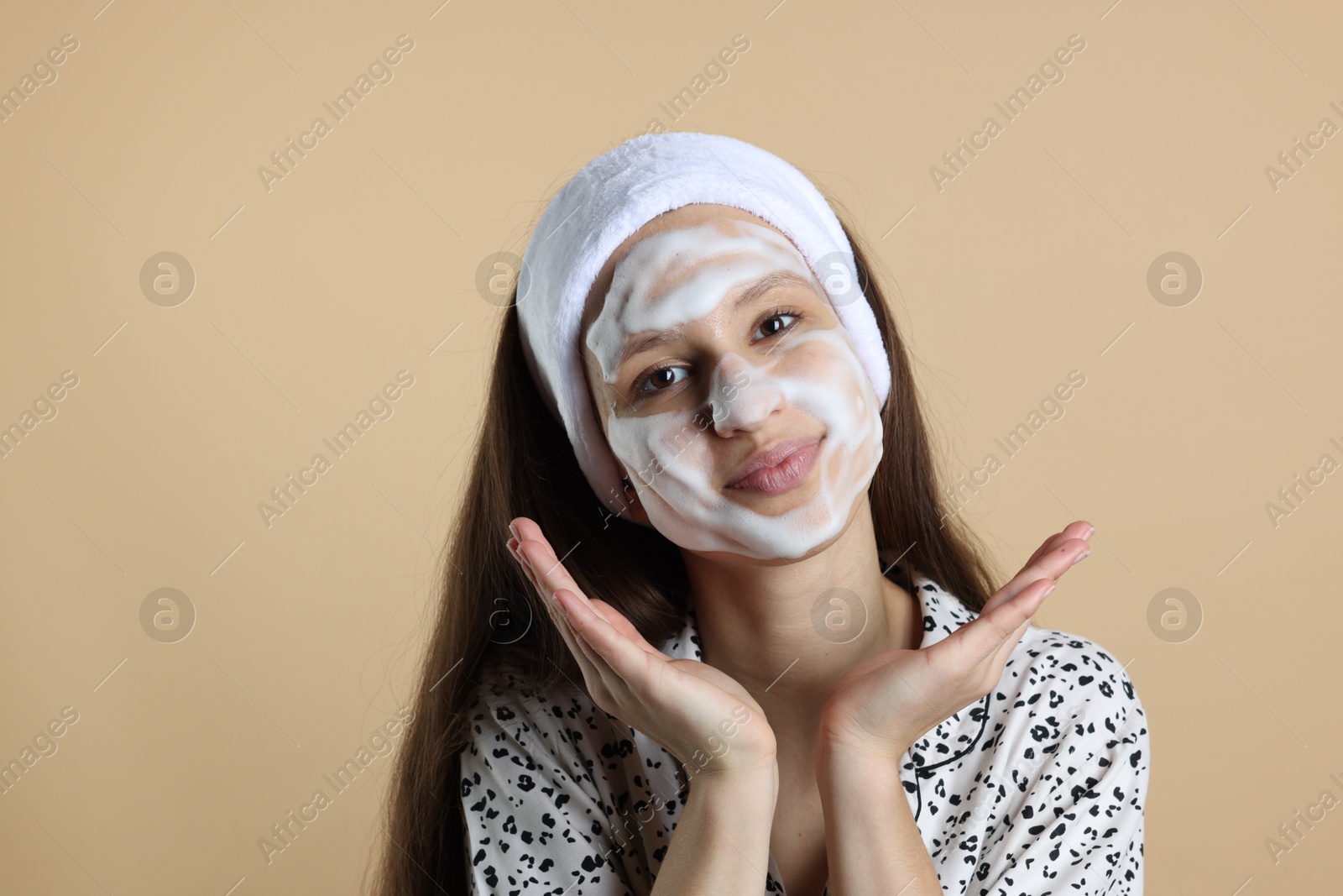 Photo of Teenage girl with cleansing foam on her face against beige background. Acne treatment