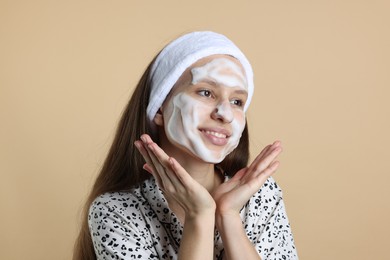 Photo of Teenage girl with cleansing foam on her face against beige background. Acne treatment