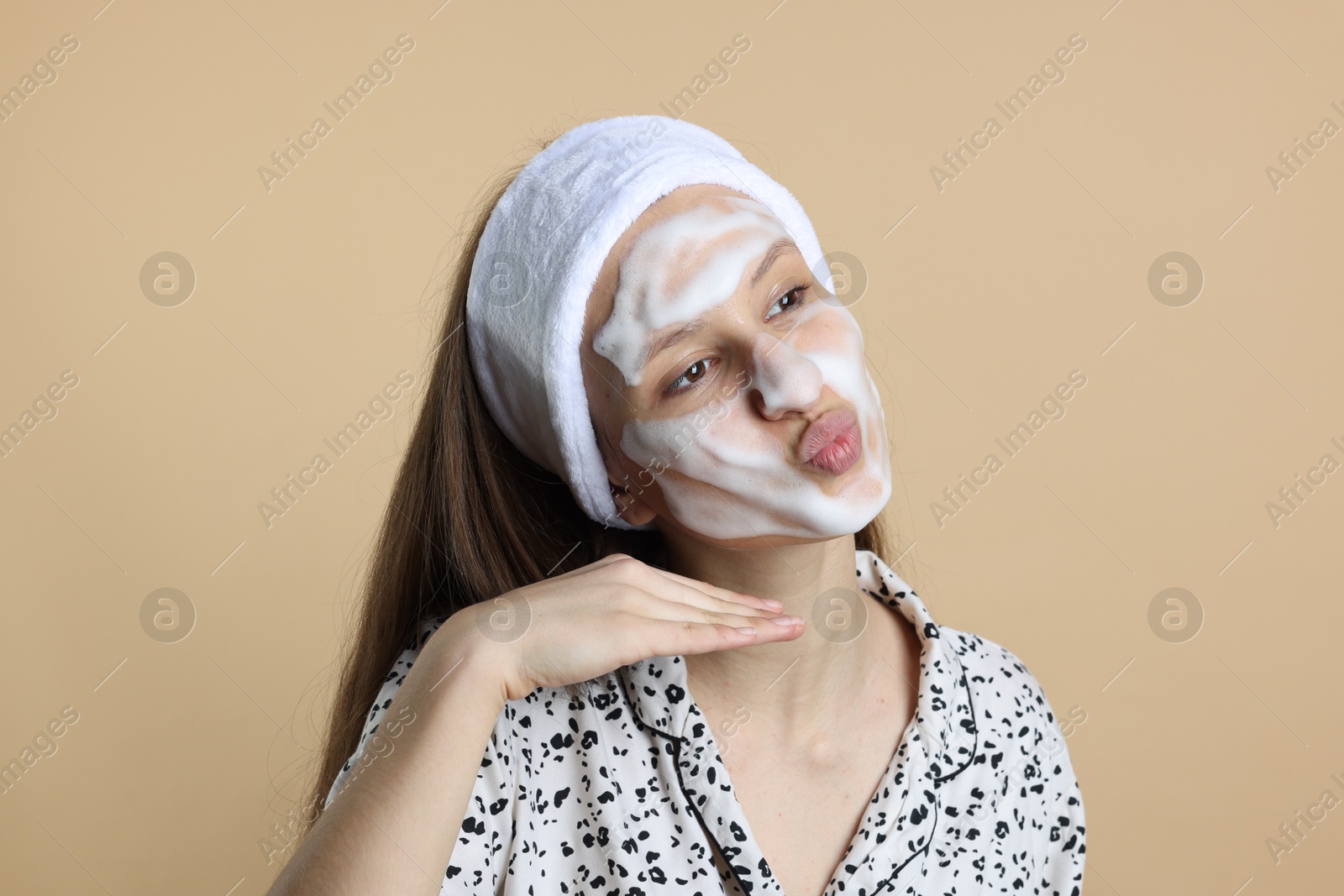 Photo of Teenage girl with cleansing foam on her face against beige background. Acne treatment