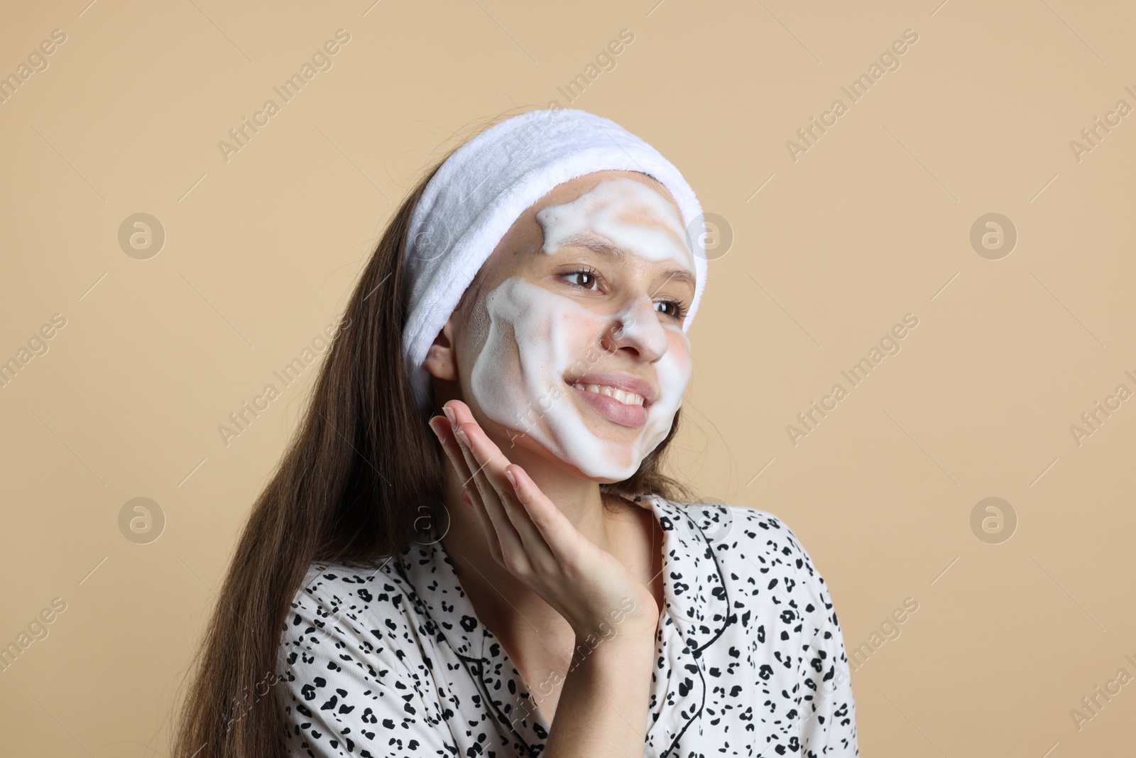 Photo of Teenage girl with cleansing foam on her face against beige background. Acne treatment