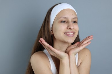 Photo of Teenage girl with acne problem on grey background