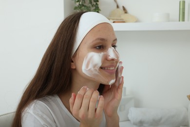 Photo of Teenage girl with cleansing foam on her face at home. Acne treatment