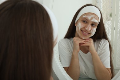 Photo of Teenage girl with cleansing foam on her face near mirror indoors. Acne treatment