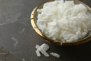 Soy wax in bowl on grey table, closeup. Space for text