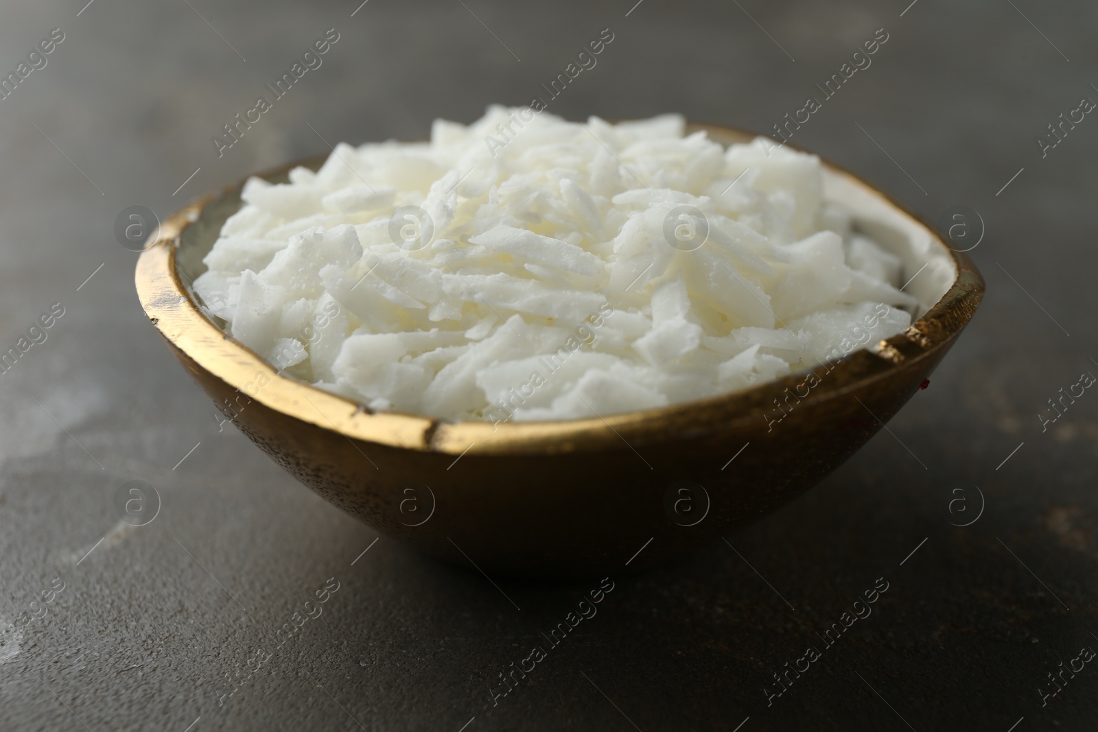 Photo of Soy wax in bowl on grey table, closeup