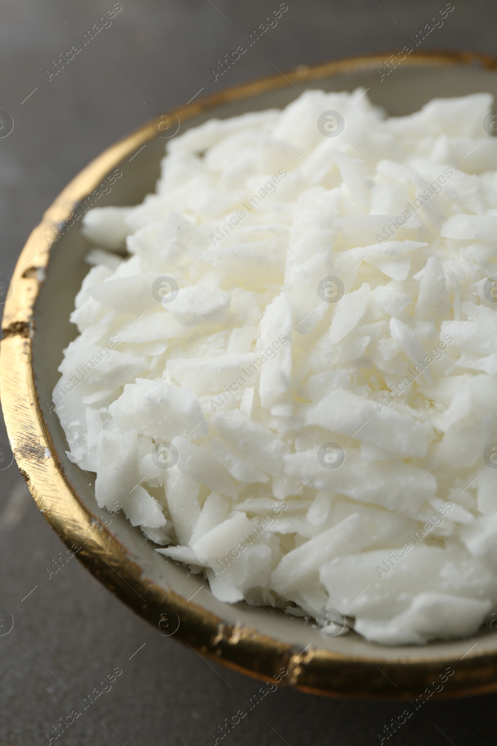 Photo of Soy wax in bowl on grey table, closeup