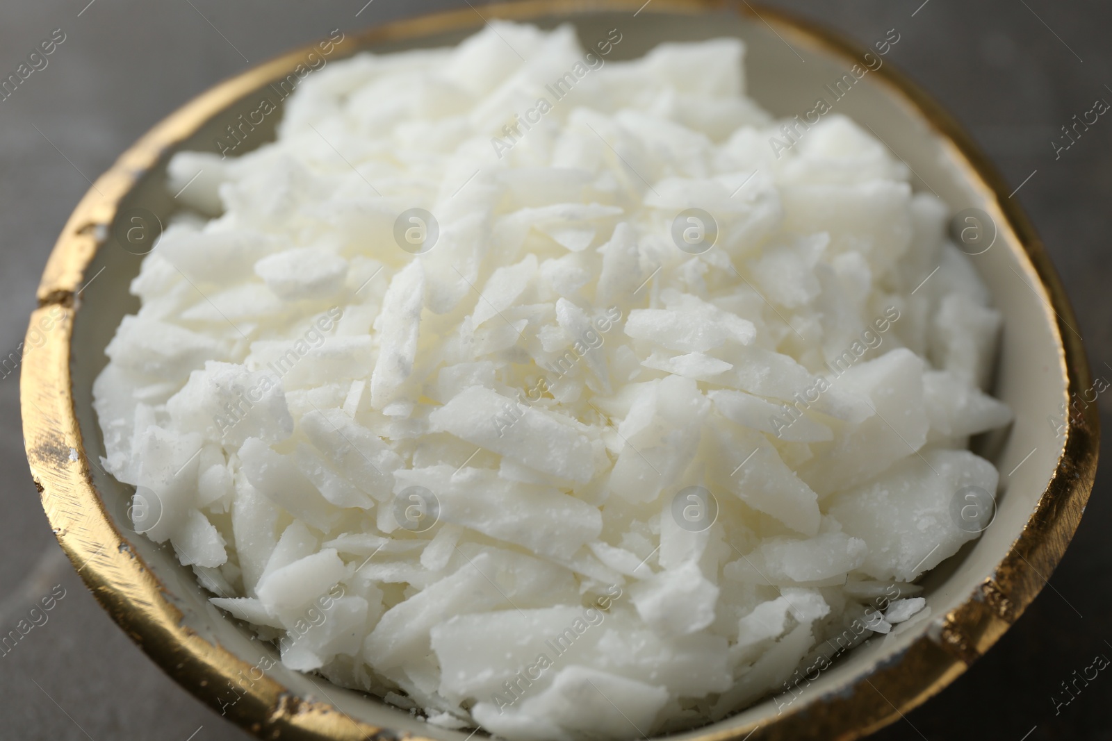 Photo of Soy wax in bowl on grey table, closeup