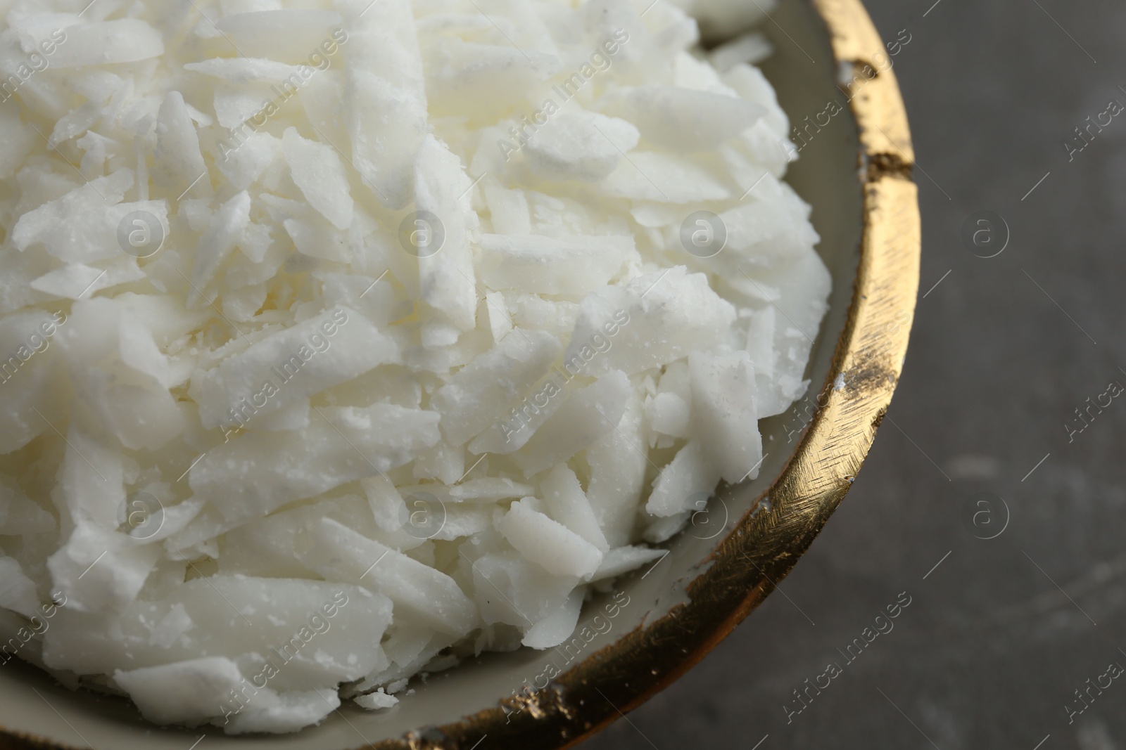 Photo of Soy wax in bowl on grey table, closeup