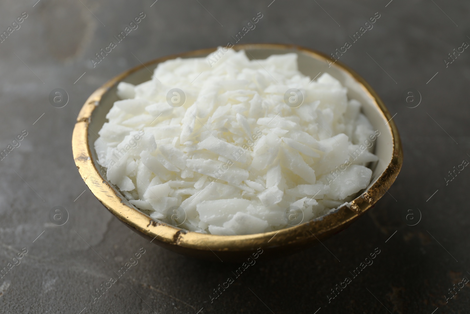 Photo of Soy wax in bowl on grey table, closeup