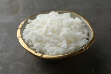 Photo of Soy wax in bowl on grey table, closeup