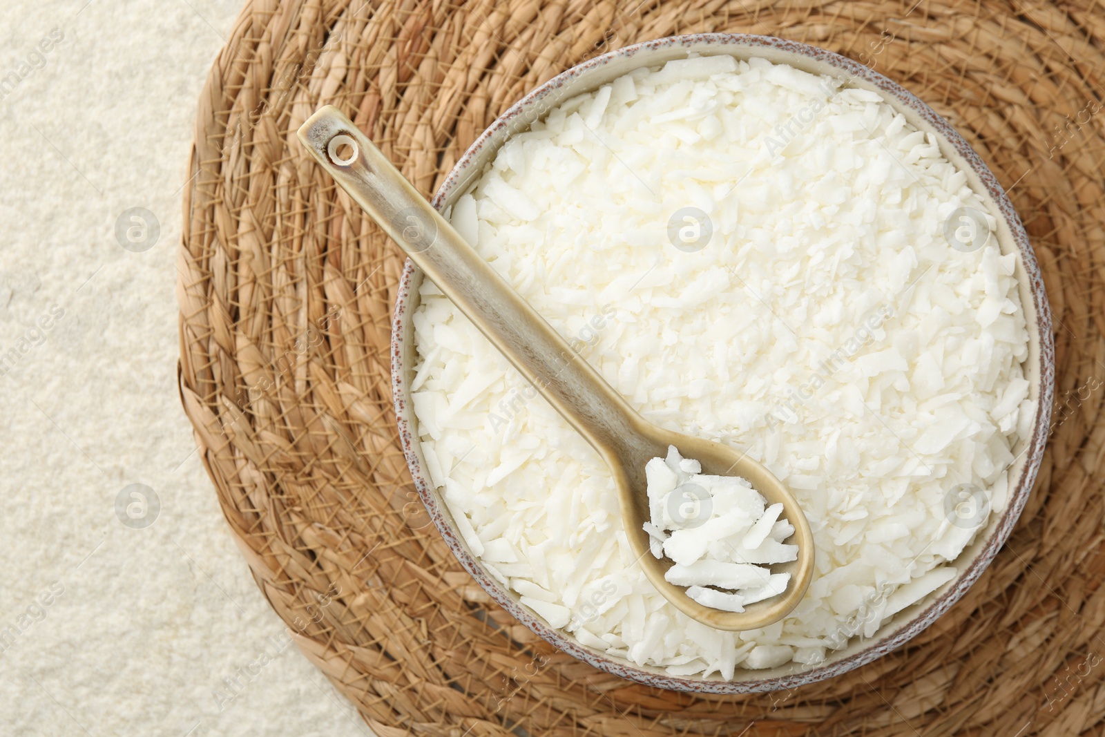 Photo of Soy wax in bowl on white textured table, top view