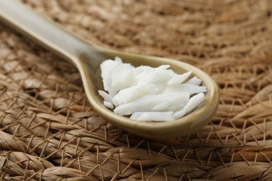 Photo of Soy wax in spoon on wicker mat, closeup