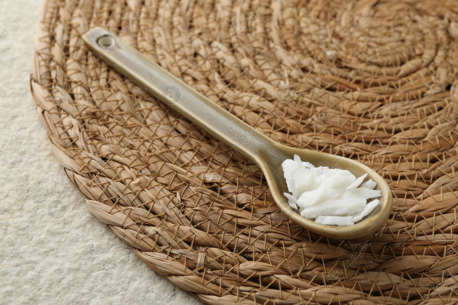 Photo of Soy wax in spoon on white textured table