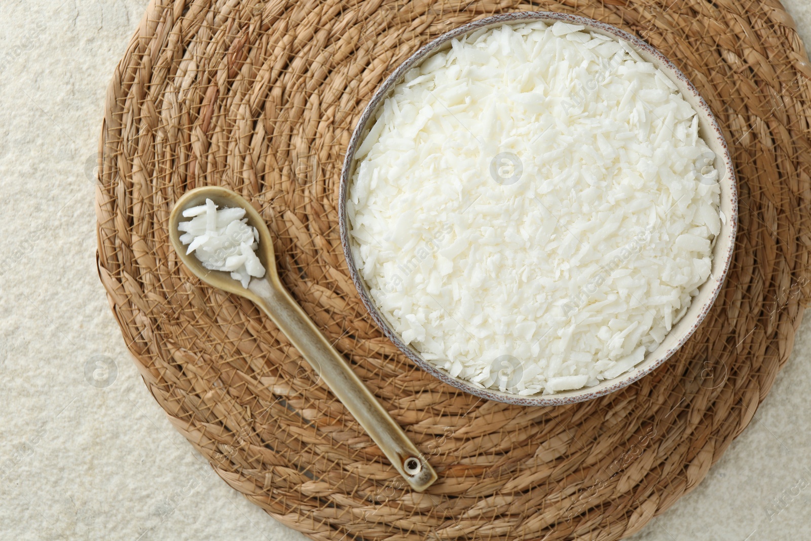 Photo of Soy wax in bowl on white textured table, top view