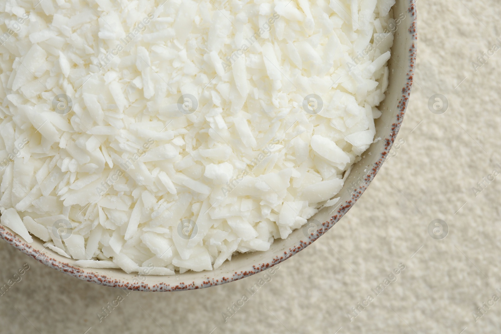 Photo of Soy wax in bowl on white textured table, top view